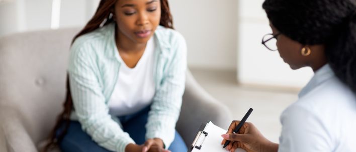 A therapist engaging in a counseling session with a male patient to support mental health.